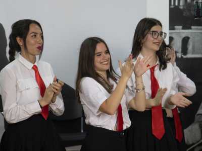 I ragazzi sono quasi tutti in tenuta di scena: una divisa scolastica costituita da camicia bianca, gonnellina o pantaloni neri e cravatta rossa...